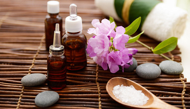 Photograph of base oil bottles and ubtan powder resting on a woven mat before starting a home spa treatment.