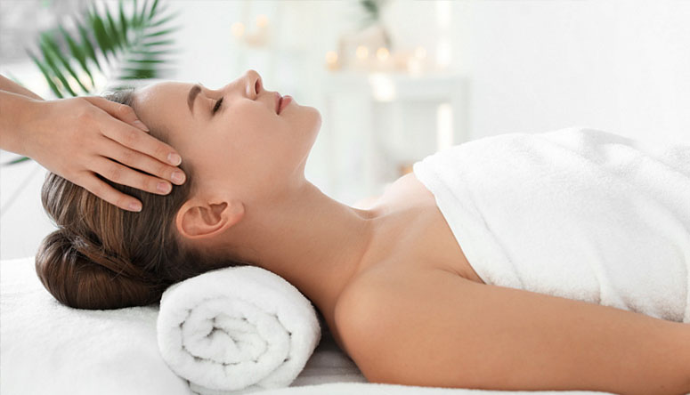 Photo of a person wrapped in white towels resting peacefully to integrate therapeutic benefits after an oil massage.