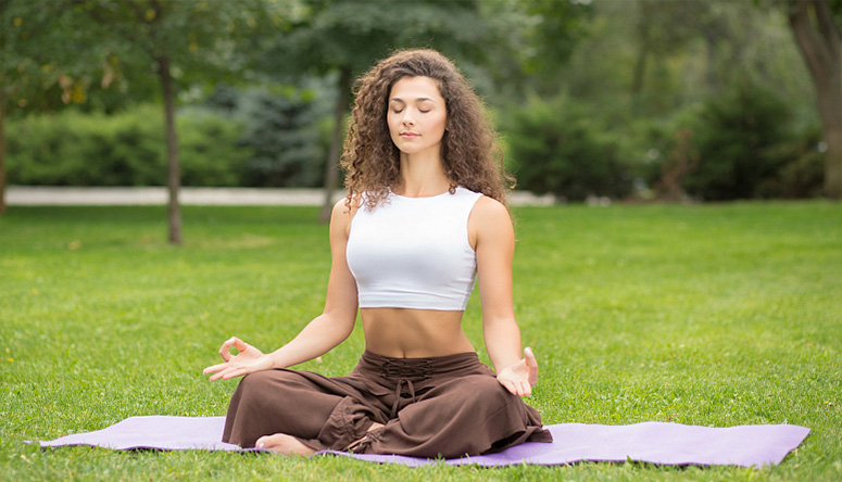 Woman practicing meditation in nature to balance Pitta dosha and maintain internal coolness during summer heat
