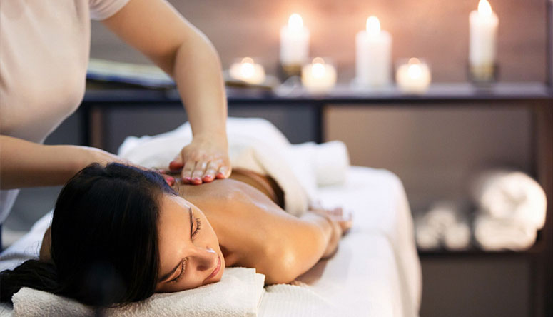 Photo of a practitioner's hands applying warm herbal oil for detoxification during an Ayurvedic Abhyanga massage.
