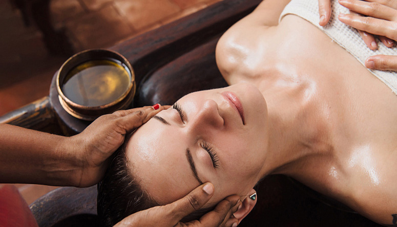 Photo of a serene woman receiving a traditional head massage for deep relaxation and holistic rejuvenation.