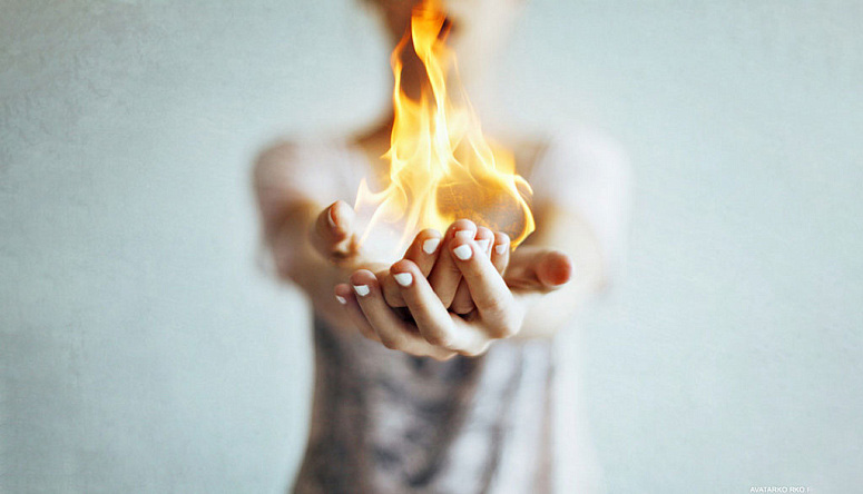 Close-up of hands gently holding a flame illustrating conscious control over internal energy and emotional state