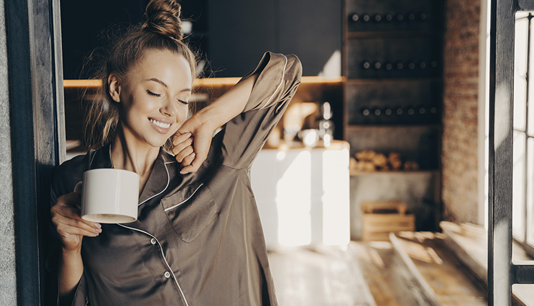 Happy woman in pyjamas enjoying the morning and the state of Ojas vitality for health