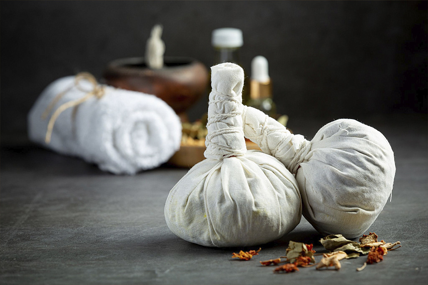 Photo of two prepared cotton poultices standing on a dark background next to essential oils for aromatherapy.