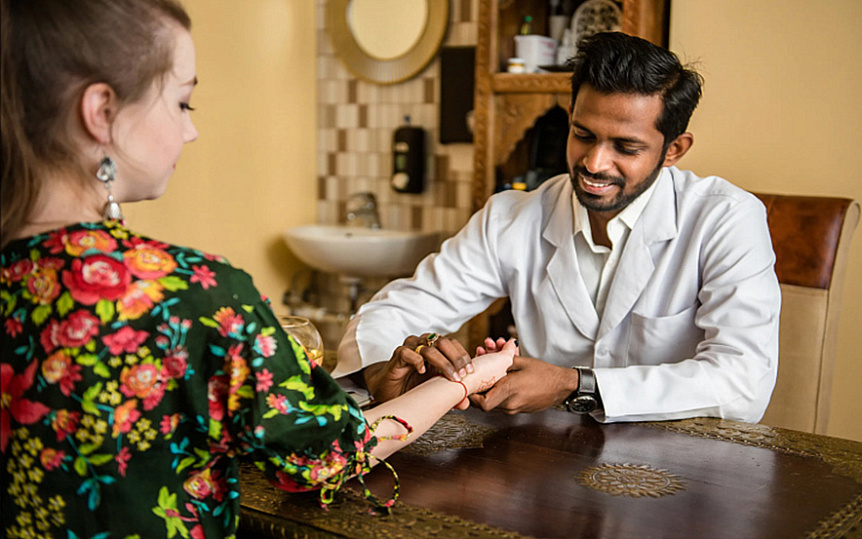Photo of an Ayurvedic doctor measuring a patient pulse during a clinical pre-Shirodhara consultation.
