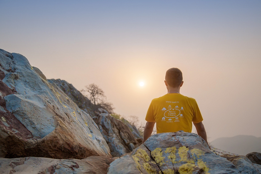 Person meditating on a beach at sunset to start the restorative Empty Bowl practice.