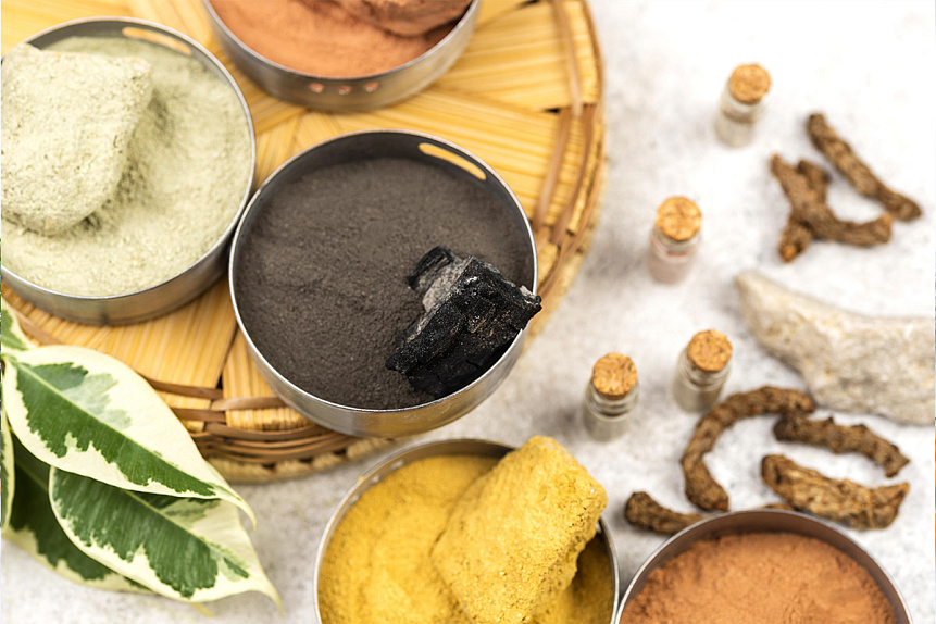 Photo of metal bowls containing colorful herbal powders prepared for Ayurvedic home treatment.