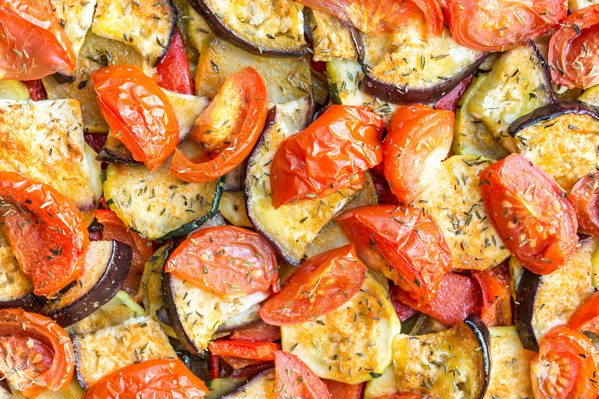 Photo of baked vegetable ratatouille garnished with fresh basil for a hearty Ayurvedic dinner.