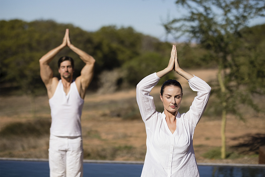 Photo of a couple practicing yoga outdoors demonstrating an Ayurvedic lifestyle for body and mind balance.