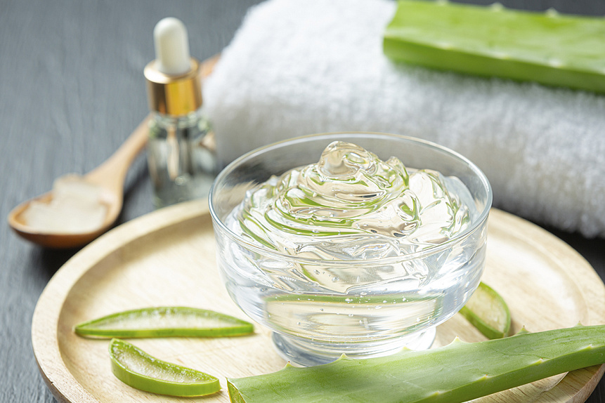 Photo of transparent aloe vera gel in a glass bowl and fresh leaves symbolizing a natural remedy for soothing the skin.