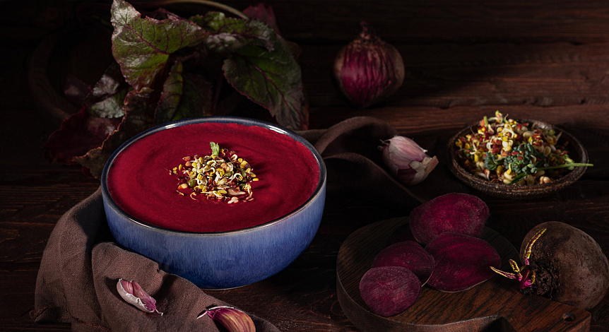 Photo of beetroot cream soup in a blue bowl placed on a table for a warming winter lunch.