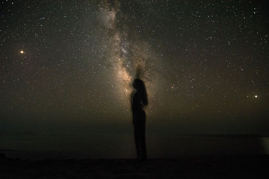 Human silhouette filled with stars and galaxies against a deep space background visualizing the microcosm-macrocosm link