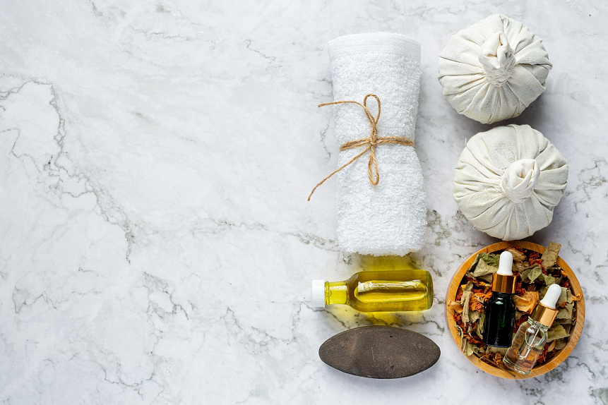 Flat lay photo of a wellness spa kit with a towel, herbal stamps, and ubtan powder for gentle oil removal
