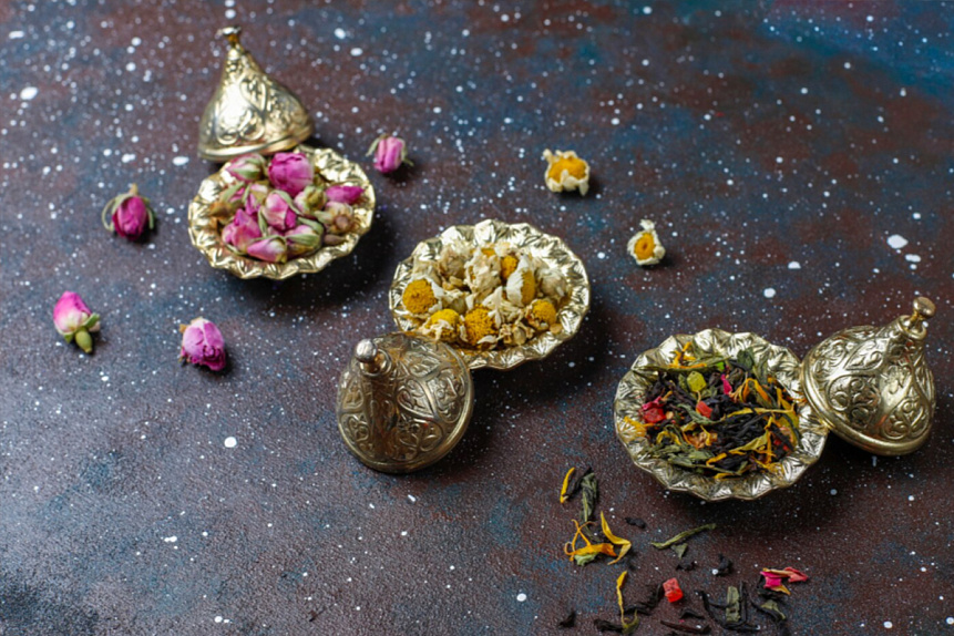 Photo of golden decorative bowls filled with dried rose buds and chamomile prepared for individualized dosha balancing.