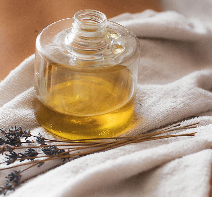 Photo of two glass bottles containing golden Ayurvedic massage oil on a textured wooden table.