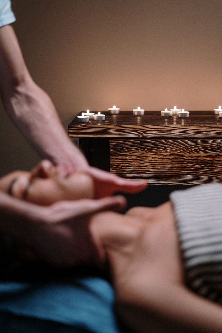 Photo of a relaxed woman getting a specialized Ayurvedic facial massage from a professional therapist.