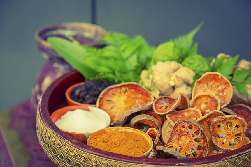 Photo of a wooden bowl containing dried herbs and spices collected for ayurvedic therapy sessions.