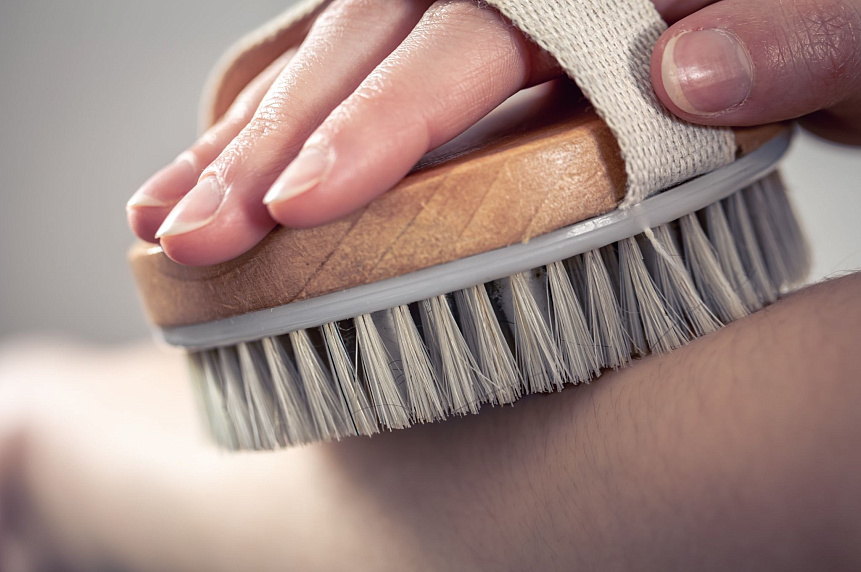 Close-up photo of a hand brushing bare skin, demonstrating how to perform Garshana massage safely.