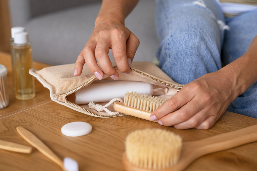 Photograph of a person packing a wooden brush into a canvas bag, showing proper massage tool care.