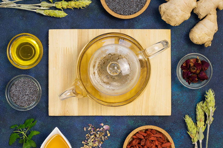 Photo of a glass teapot with a herbal infusion surrounded by spices, traditionally used to relieve menstrual pain.