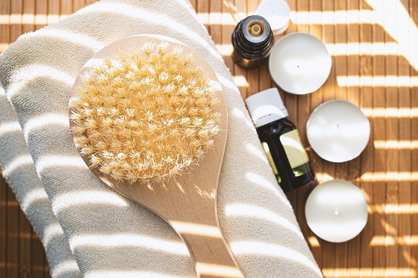 Photograph of a wooden dry brush on a towel with candles, illustrating relaxing Ayurvedic spa benefits.