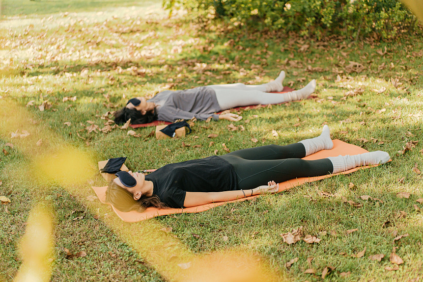 A men in Shavasana pose resting outdoors in shade to calm internal heat and support holistic Ayurvedic skin health.