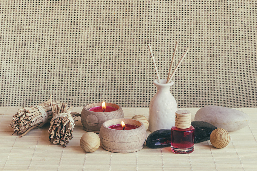 Photo of burning candles and essential oil on a bamboo mat demonstrating natural aromatic insect protection methods.