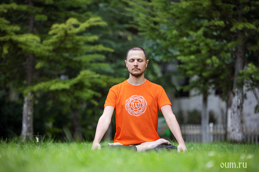 Photo of a man meditating in lotus pose on green grass illustrating inner peace and mindfulness.