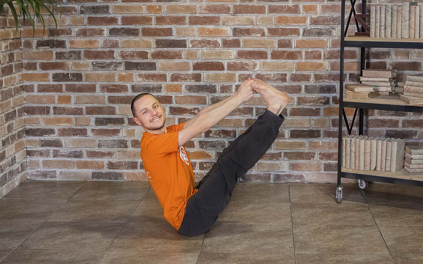 Photograph of a man performing Full Boat Pose (Paripurna Navasana) as a recommended yoga asana for Pitta dosha balance.