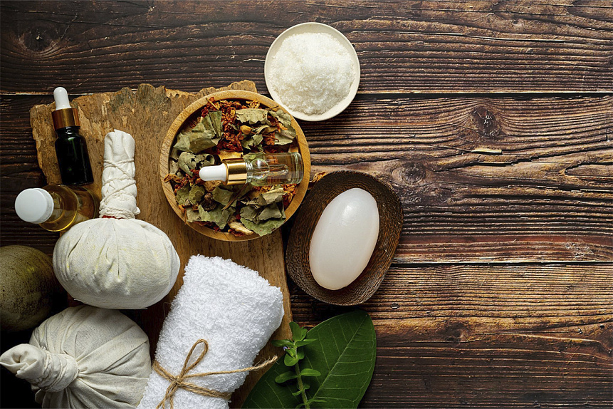 Photo of natural ingredients and cotton poultices lying on a rustic table for Ayurvedic massage preparation.
