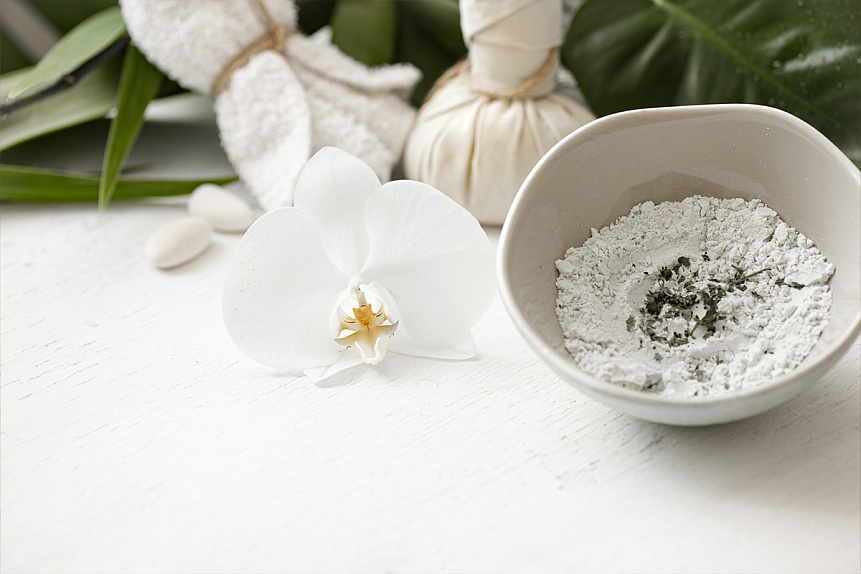 Photo of a ceramic bowl with herbal powder resting on a wooden table for Ayurvedic skin care.