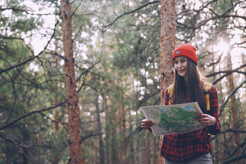 Photograph of a woman hiking in a pine forest practicing healthy lifestyle habits